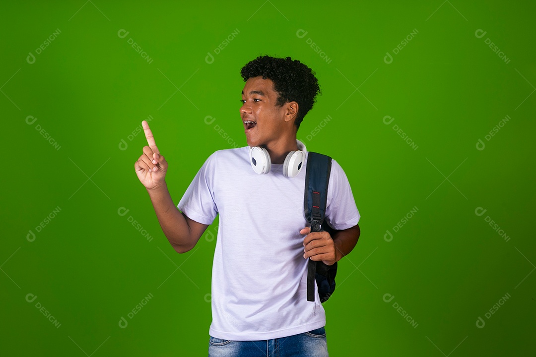 Lindo garoto negro de camisa branca usando bolsa e fone de ouvido sobre fundo verde isolado