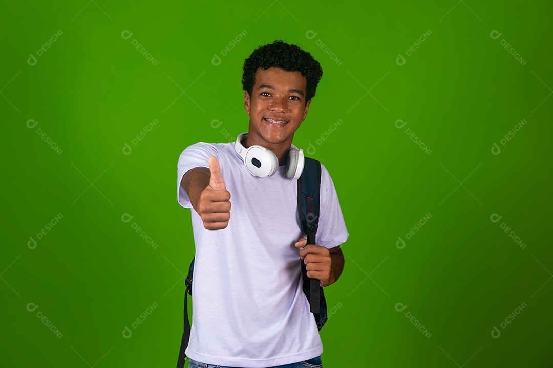 Lindo garoto negro de camisa branca usando bolsa e fone de ouvido sobre fundo verde isolado