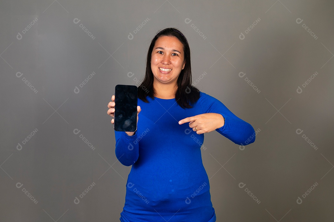 Linda mulher de blusa azul segurando smartfhone sobre fundo isolado