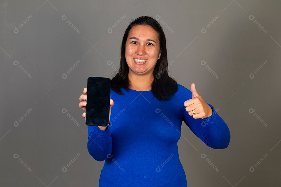 Linda mulher de blusa azul segurando smartfhone sobre fundo isolado