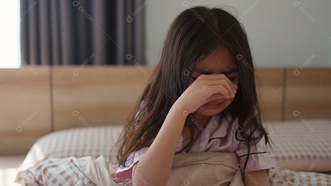 Linda menina assustada no quarto chorando com as mãos segurando seu ursinho com medo sobre fundo desfocado
