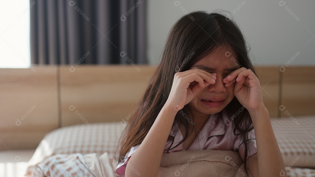 Linda menina assustada no quarto chorando com medo sobre fundo desfocado