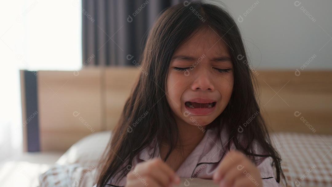 Linda menina assustada no quarto chorando com medo sobre fundo desfocado
