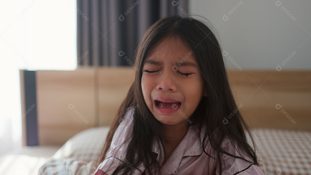 Linda menina assustada no quarto chorando com medo sobre fundo desfocado