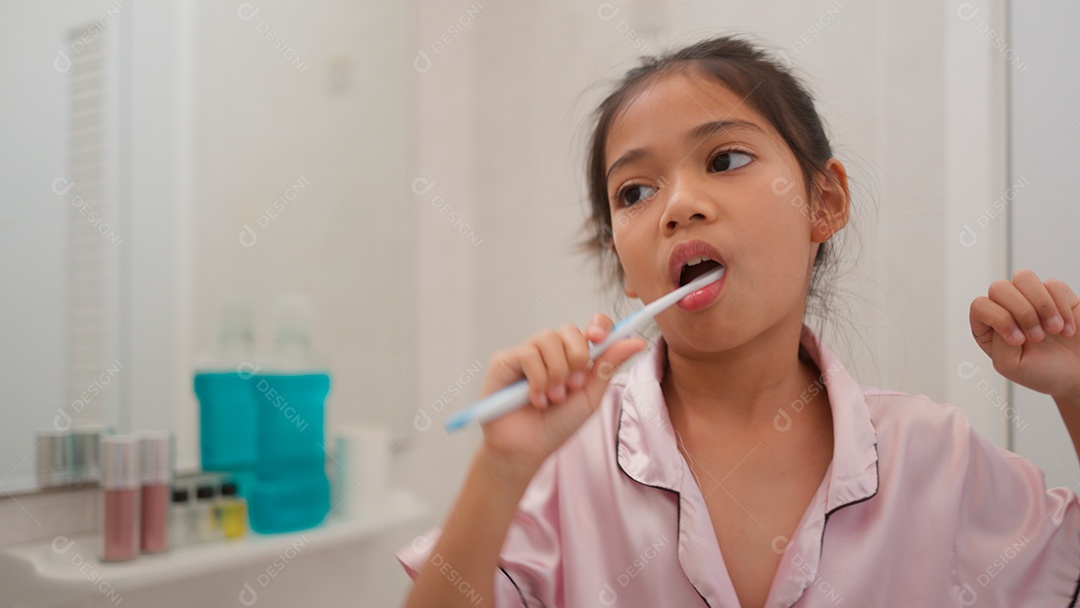 Linda menina com roupa de dormir escovando os dentes sobre fundo isolado