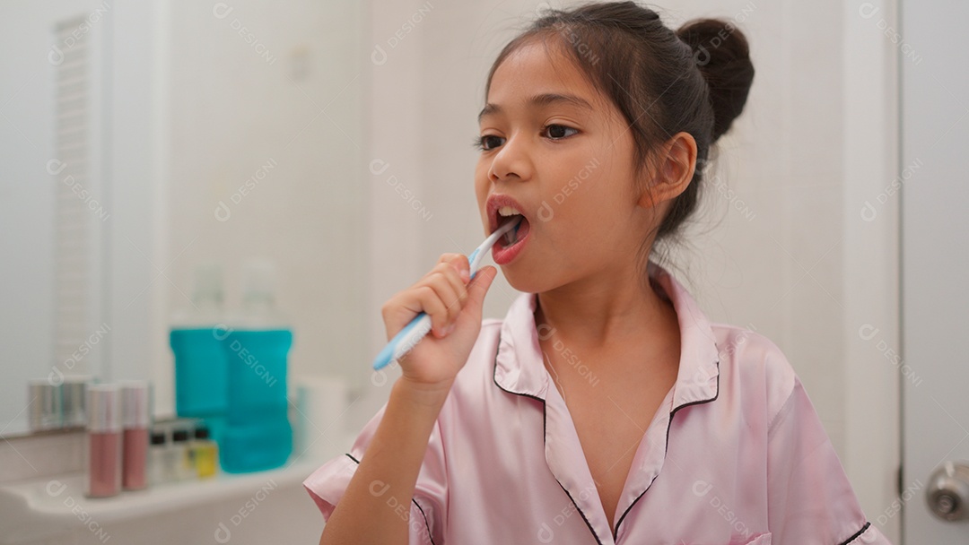 Linda menina com roupa de dormir escovando os dentes sobre fundo isolado