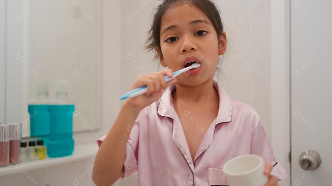Linda menina com roupa de dormir escovando os dentes sobre fundo isolado