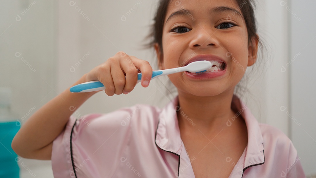 Linda menina com roupa de dormir escovando os dentes sobre fundo isolado