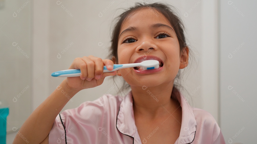 Linda menina com roupa de dormir escovando os dentes sobre fundo isolado