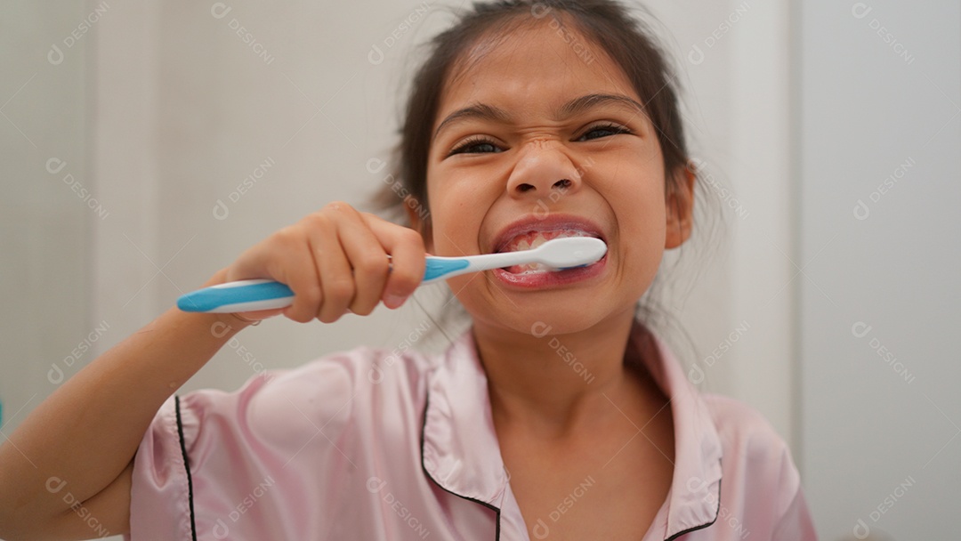 Linda menina com roupa de dormir escovando os dentes sobre fundo isolado