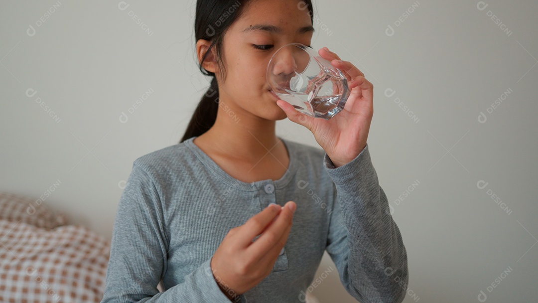 Linda menina sentada sobre sua cama tomando rémedio para dor desconfortável