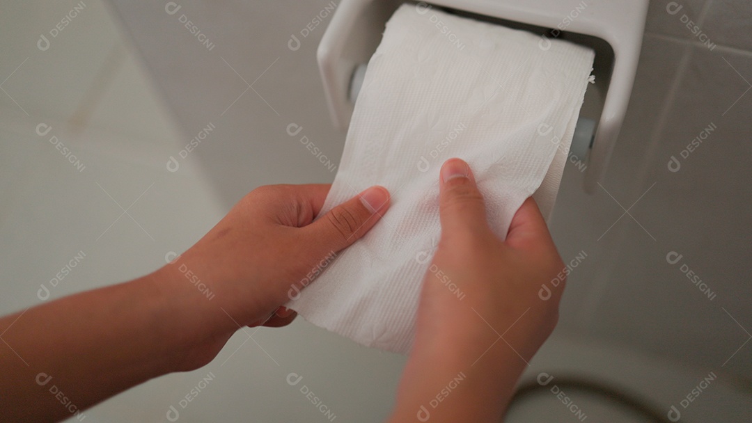 Mão de menina desenrolando papel higiênico sobre fundo isolado