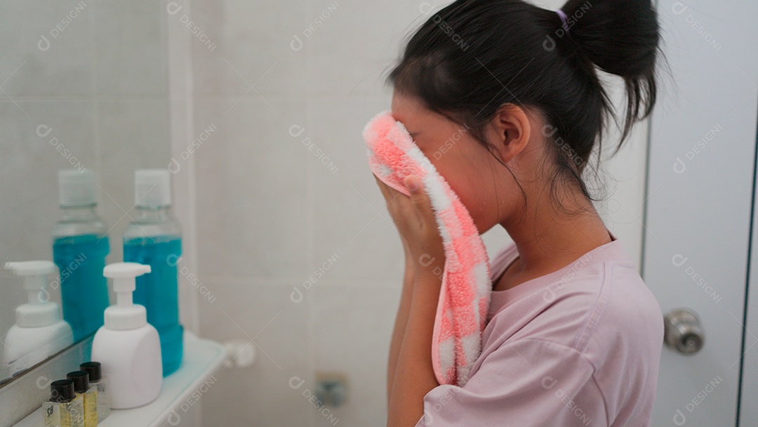 Linda menina asiática enfrente ao espelho enxugando o rosto