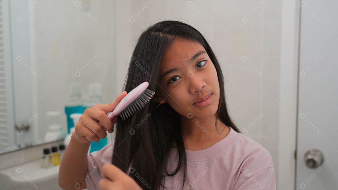 Linda menina asiática enfrente ao espelho  escovando o cabelo