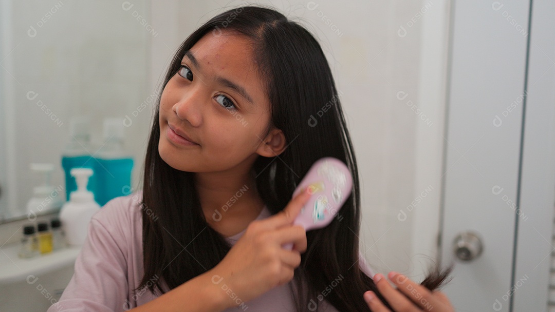 Linda menina asiática enfrente ao espelho  escovando o cabelo