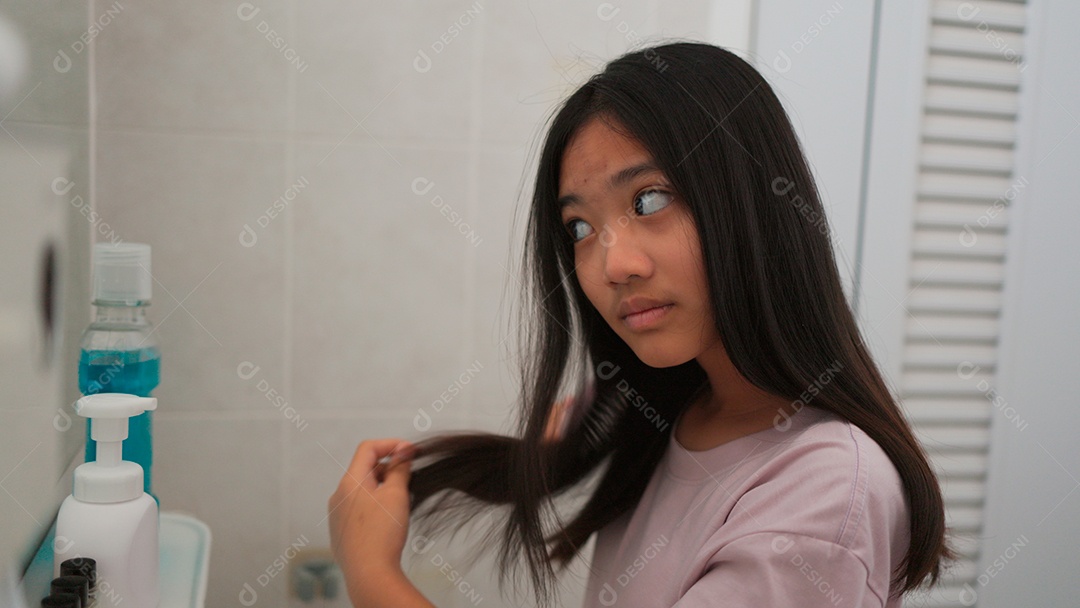 Linda menina asiática enfrente ao espelho  escovando o cabelo