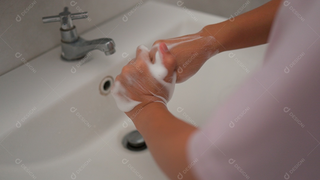 Linda menina asiática lavando as mãos sobre uma pia