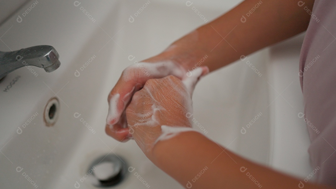 Linda menina asiática lavando as mãos sobre uma pia