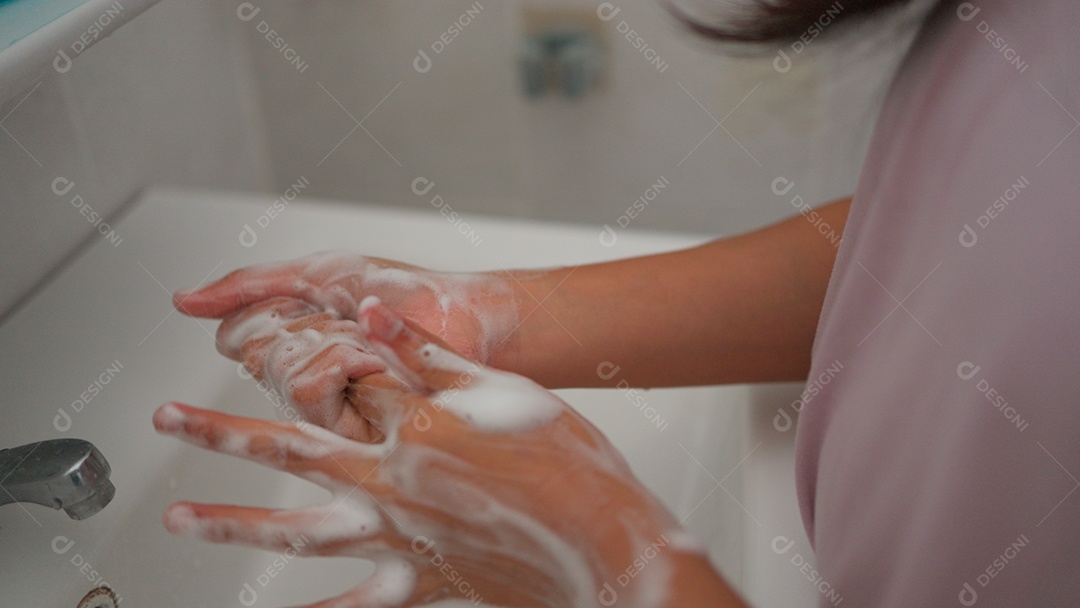 Linda menina asiática lavando as mãos sobre uma pia