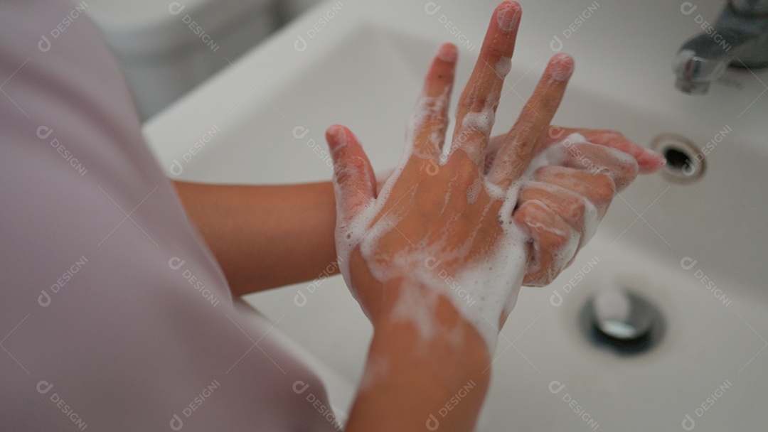 Linda menina asiática lavando as mãos sobre uma pia