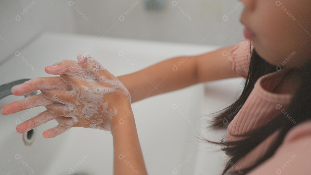 Linda menina asiática lavando as mãos sobre uma pia