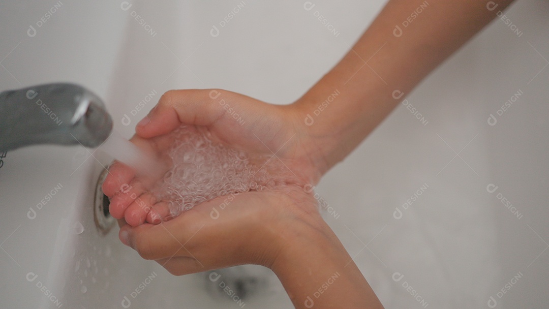 Linda menina asiática lavando as mãos sobre uma pia