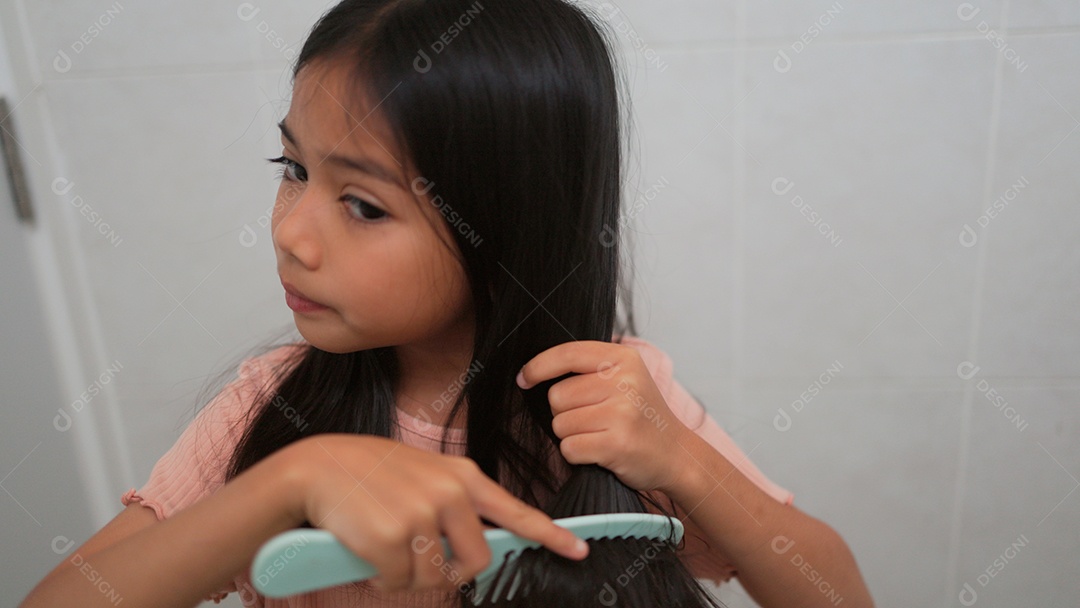 Linda menina asiática enfrente ao espelho  escovando o cabelo
