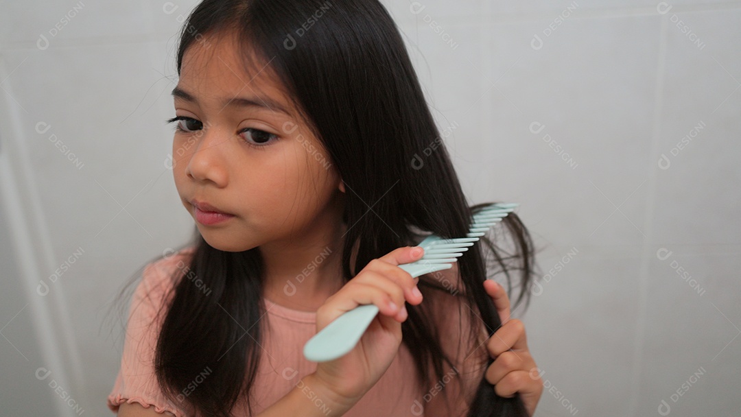 Linda menina asiática enfrente ao espelho  escovando o cabelo