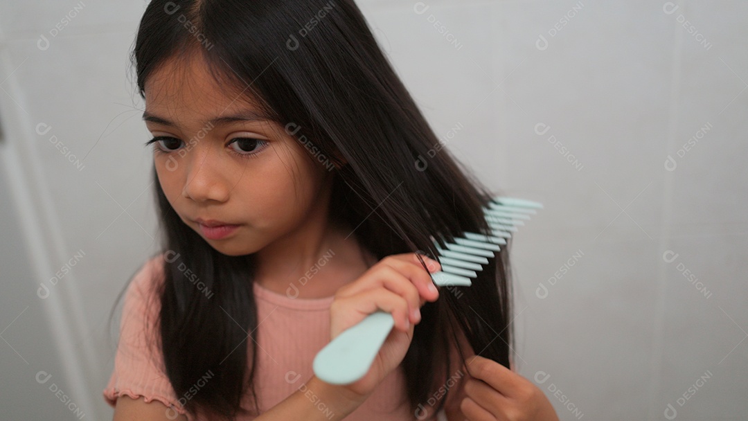 Linda menina asiática limpando escovando de cabelo sobre uma pia