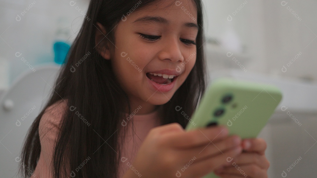 Linda menina asiática sentada em vaso sanitário mechendo em smartphone