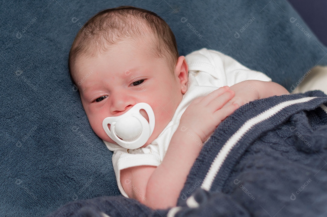 Bebê recém nascido deitado com chupeta na boca