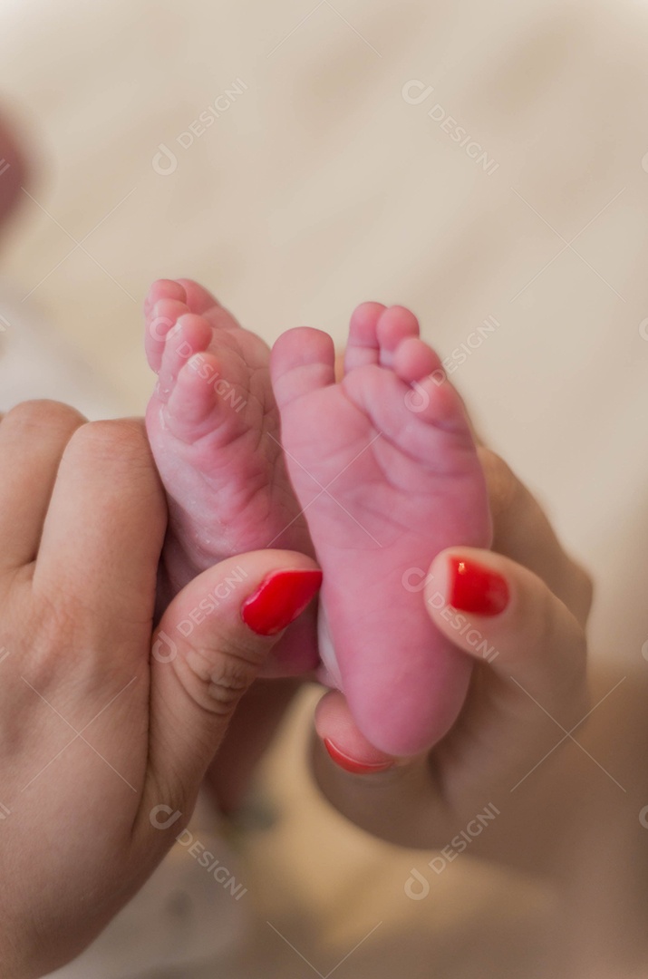 Mão de mãe segurando pezinhos de bebê recém nascido