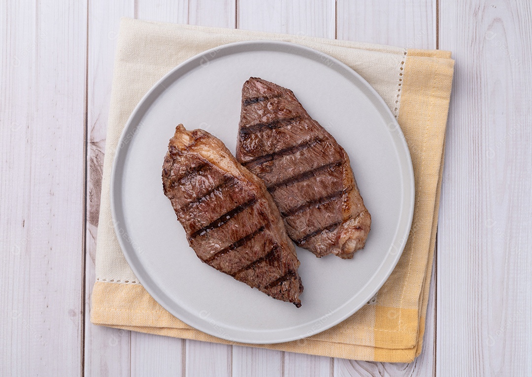 A imagem mostra dois bifes de picanha grelhada em um prato