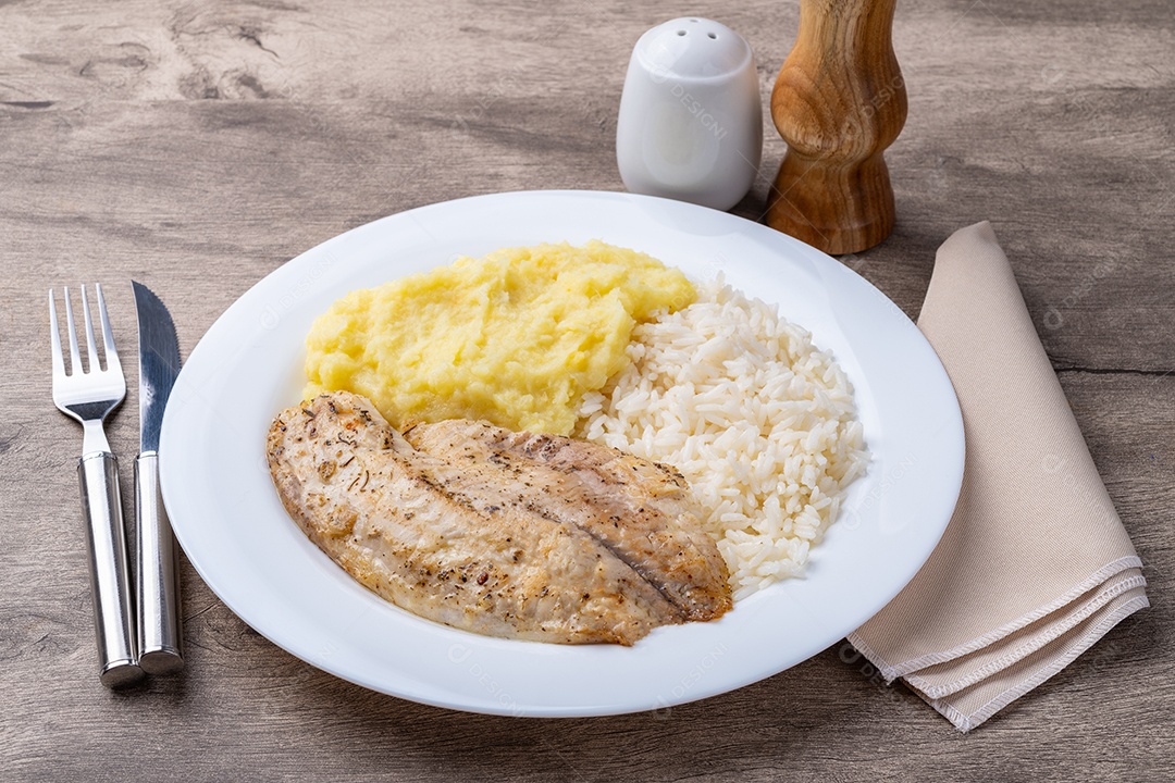 A imagem mostra um prato de filé de peixe grelhado servido com arroz branco e legumes cozidos no vapor.