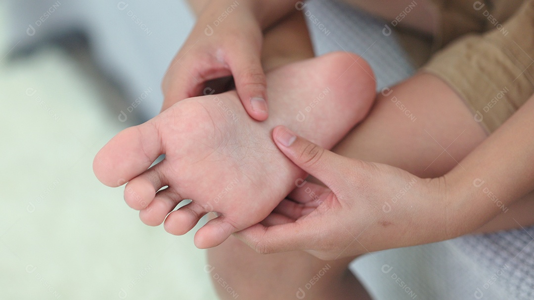 Mulher com dor descalça enquanto está sentada no sofá em casa