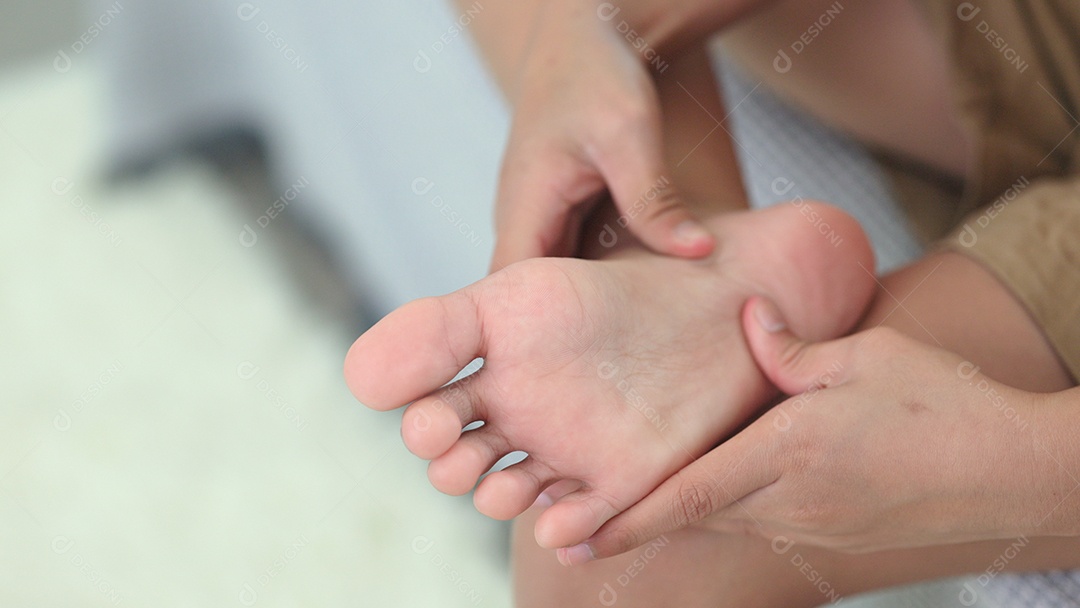 Mulher com dor descalça enquanto está sentada no sofá em casa