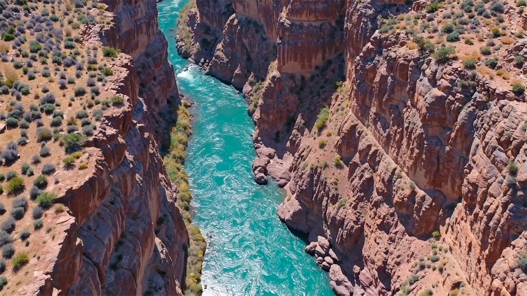 Vista aérea de um rio azul-turquesa serpenteando por um cânion profundo e rochoso MP4