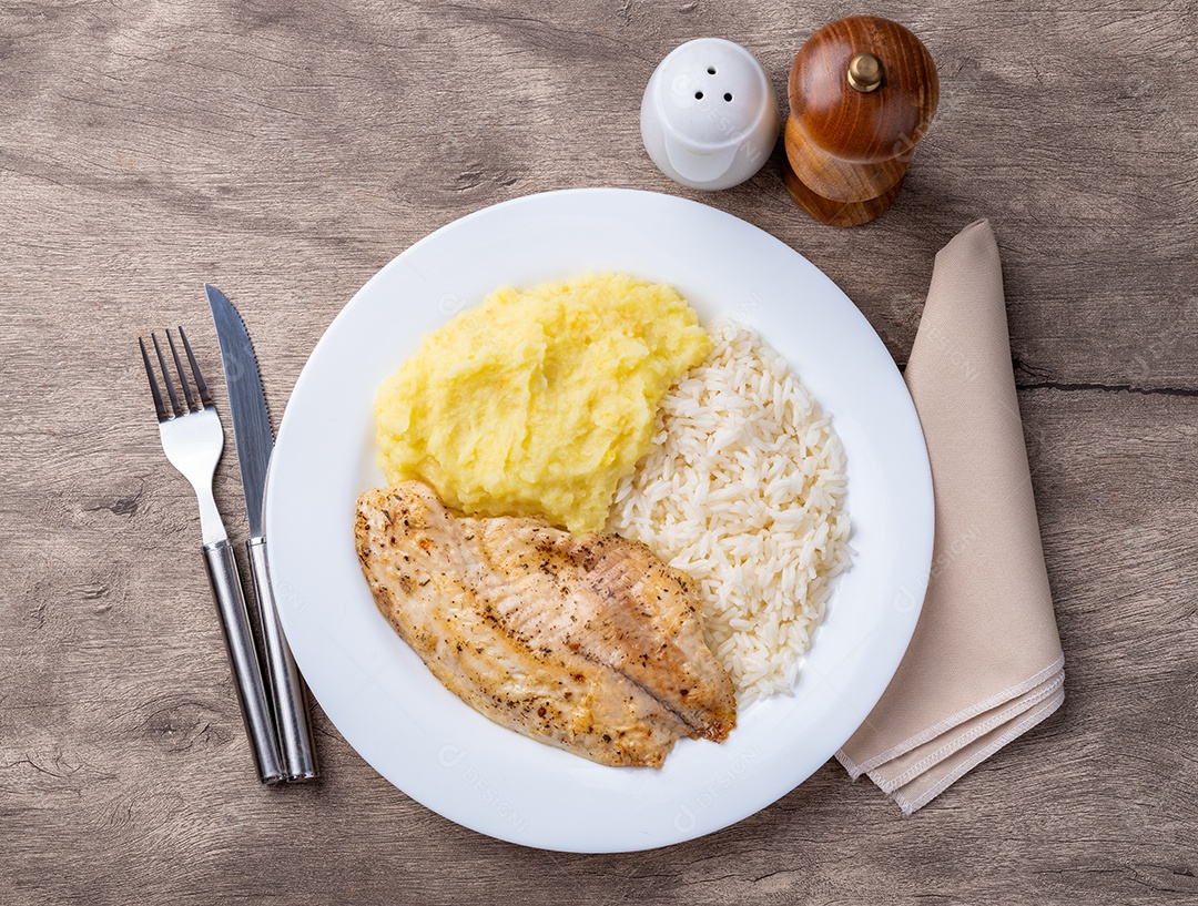 A imagem mostra um prato com filés de tilápia, purê de batata e arroz. A tilápia