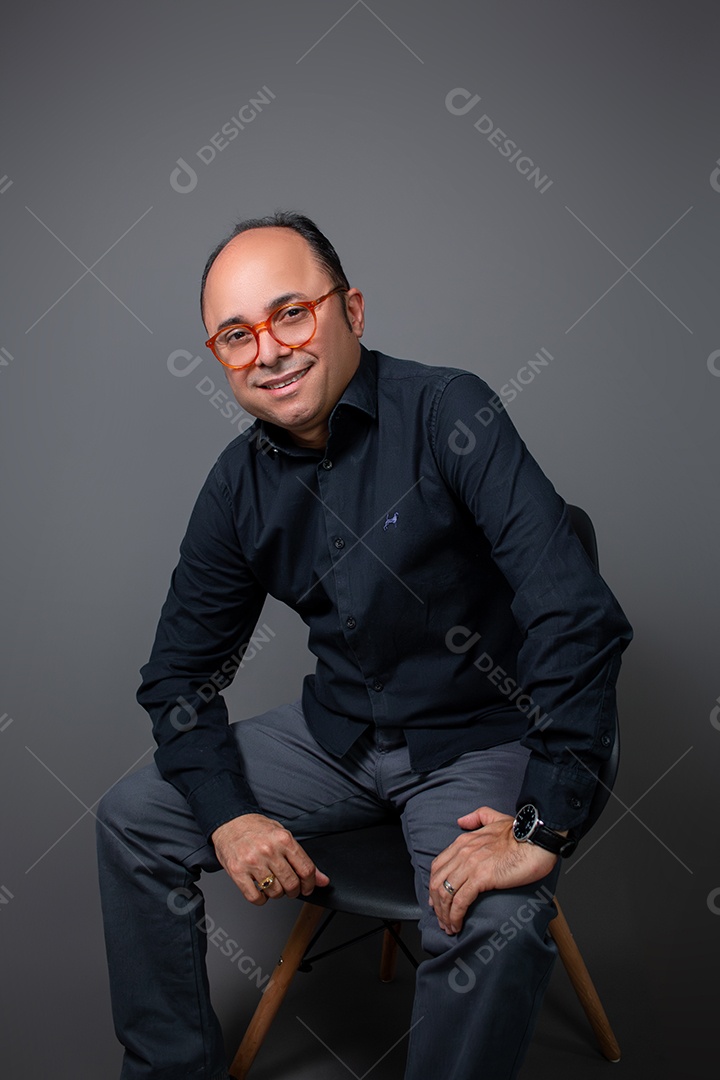 Retrato Masculino em Estúdio com Camisa Preta Posição Sentado com Mãos no Joelho Imagem
