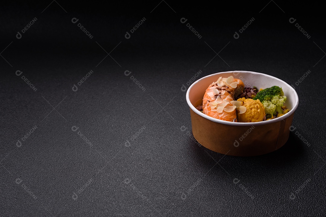 Um pedaço de salmão cozido com arroz, brócolis, sal e especiarias em um fundo de concreto escuro