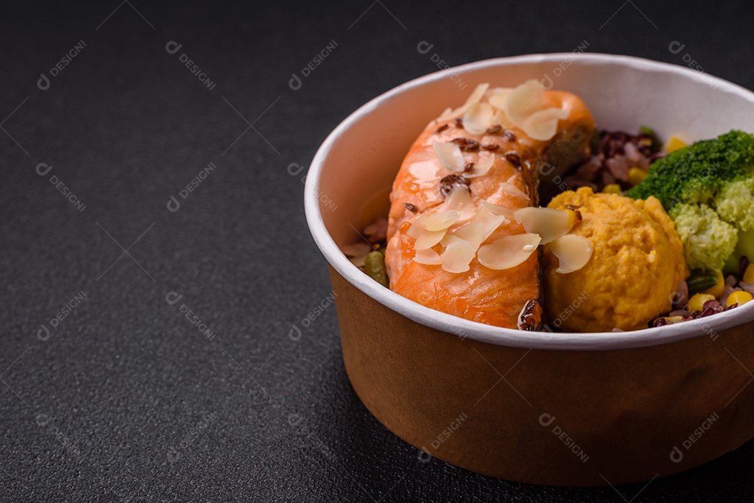 Um pedaço de salmão cozido com arroz, brócolis, sal e especiarias em um fundo de concreto escuro