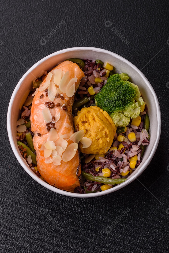 Um pedaço de salmão cozido com arroz, brócolis, sal e especiarias em um fundo de concreto escuro