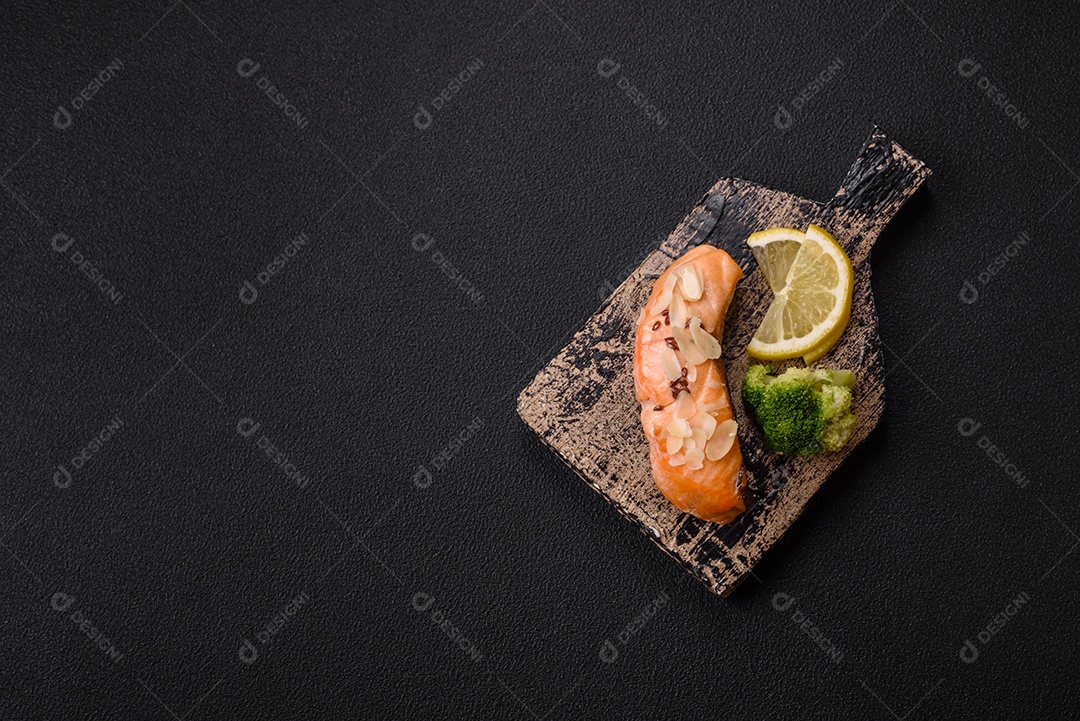 Um pedaço de salmão cozido com arroz, brócolis, sal e especiarias em um fundo de concreto escuro