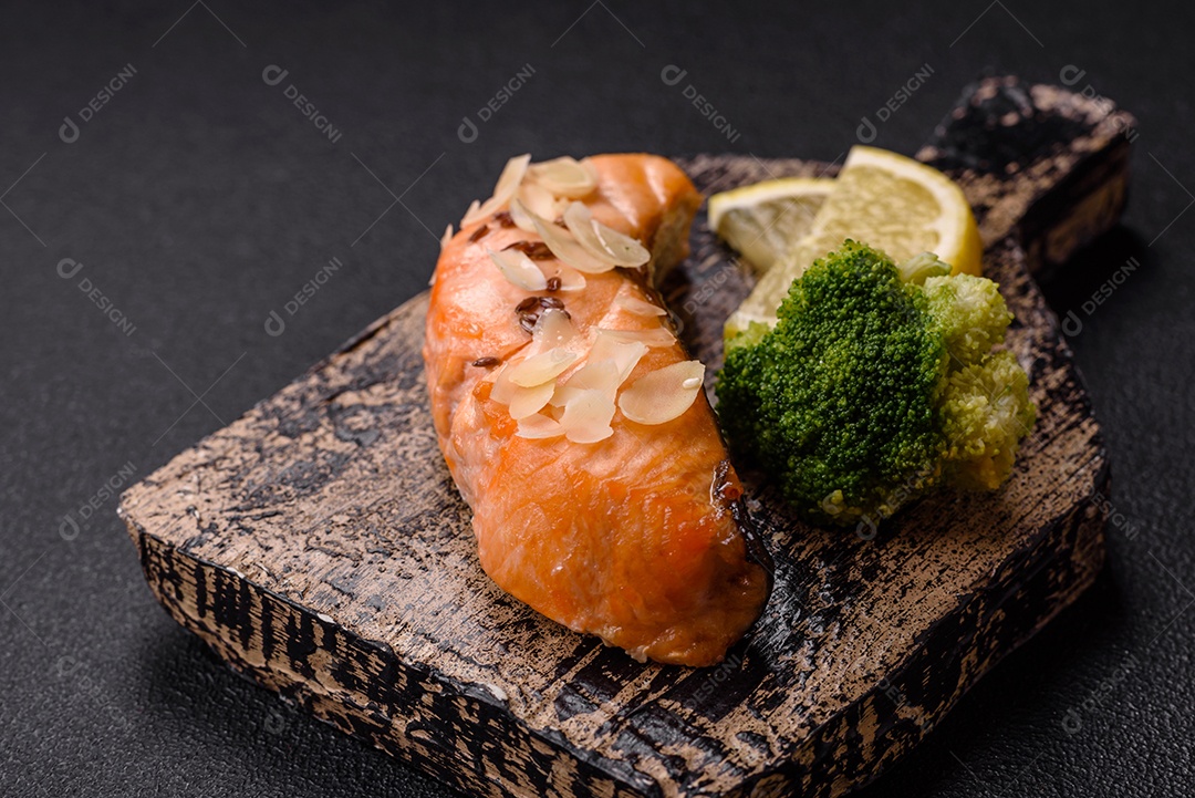 Um pedaço de salmão cozido com arroz, brócolis, sal e especiarias em um fundo de concreto escuro