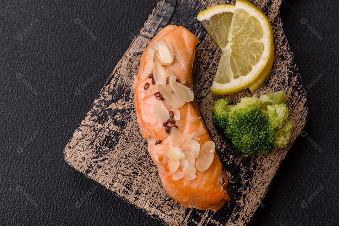 Um pedaço de salmão cozido com arroz, brócolis, sal e especiarias em um fundo de concreto escuro