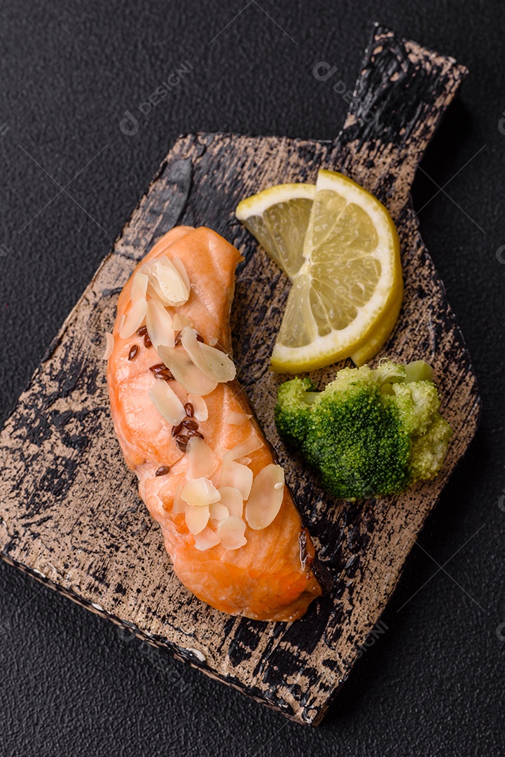 Um pedaço de salmão cozido com arroz, brócolis, sal e especiarias em um fundo de concreto escuro