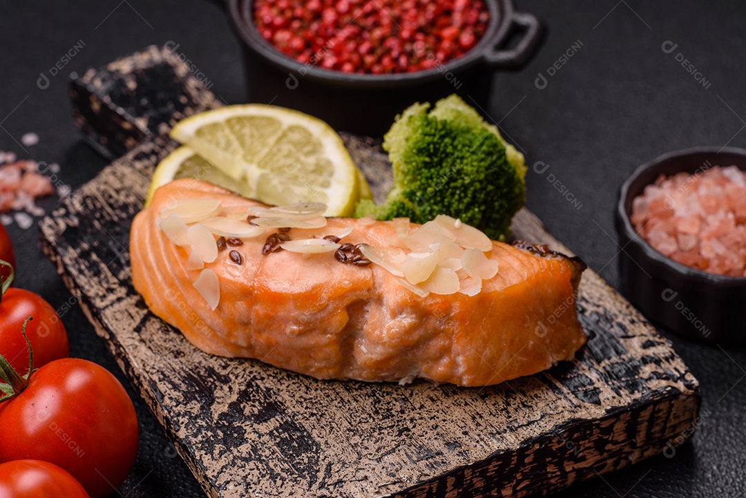 Um pedaço de salmão cozido com arroz, brócolis, sal e especiarias em um fundo de concreto escuro