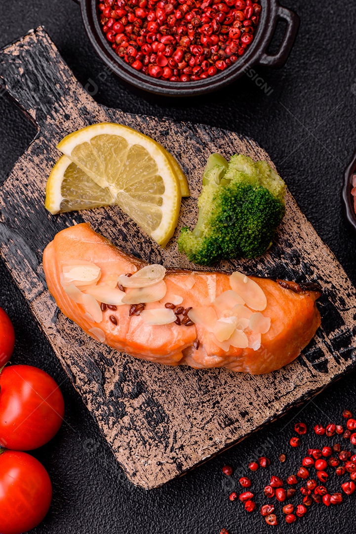 Um pedaço de salmão cozido com arroz, brócolis, sal e especiarias em um fundo de concreto escuro