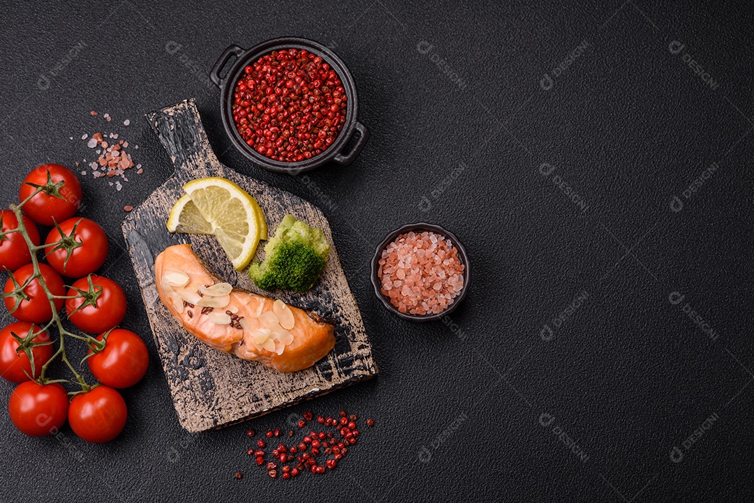 Um pedaço de salmão cozido com arroz, brócolis, sal e especiarias em um fundo de concreto escuro
