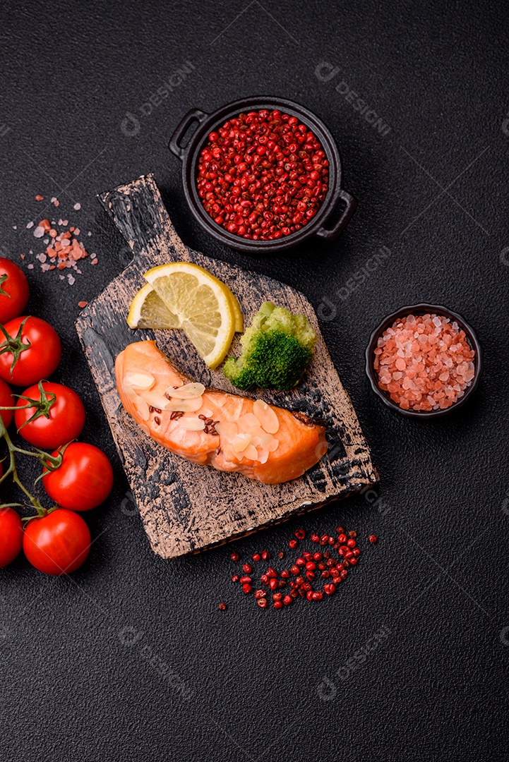 Um pedaço de salmão cozido com arroz, brócolis, sal e especiarias em um fundo de concreto escuro